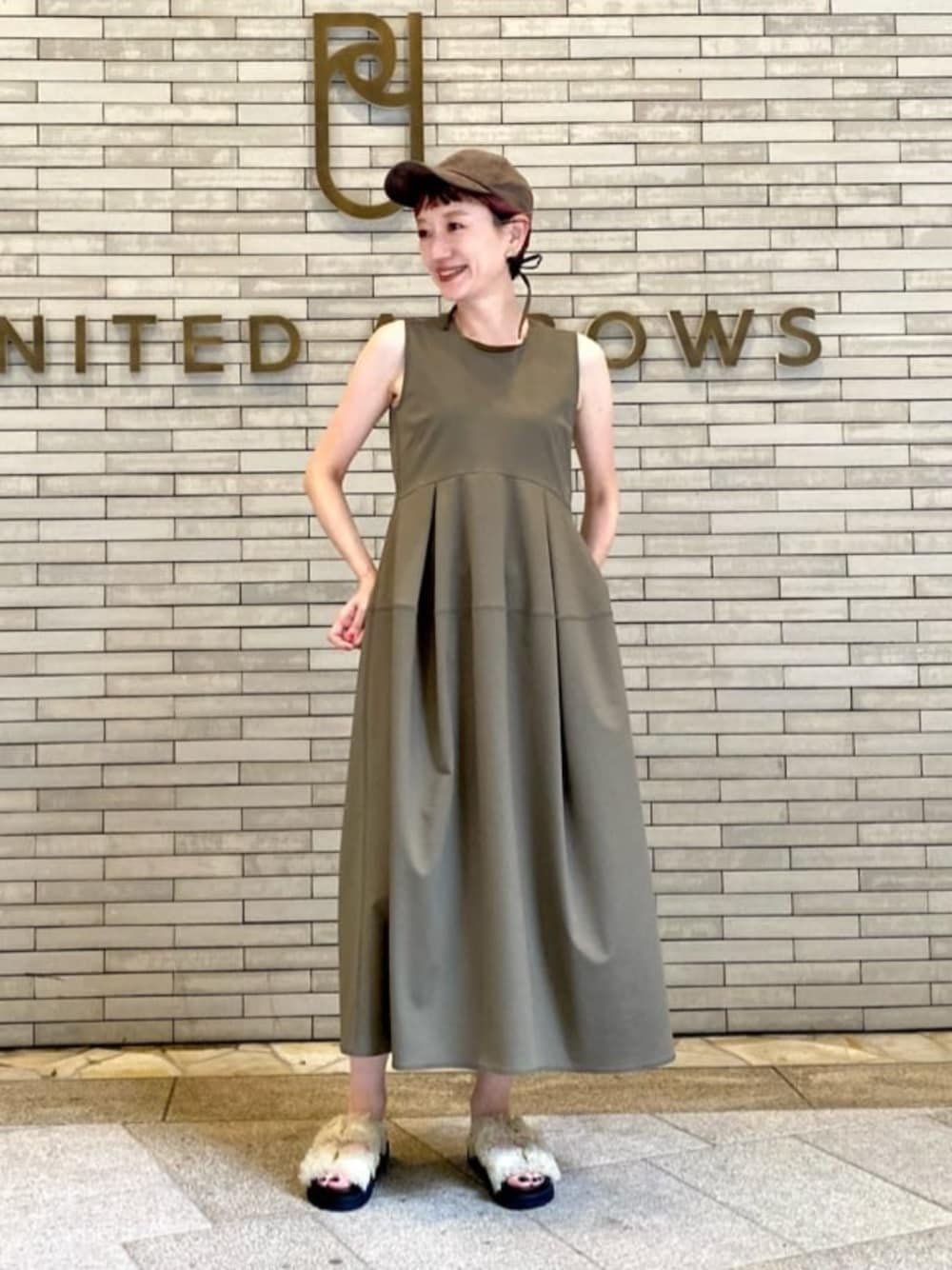 グリーン系のワンピース、ホワイト系のサンダル、ゴールド系のイヤリングを着用したレディースの夏コーディネートの1枚目の写真