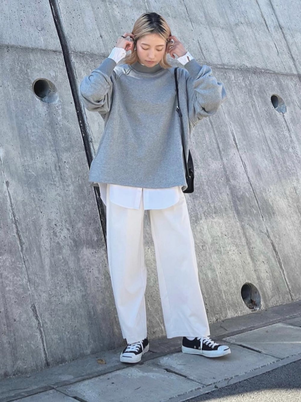 グレー系のスウェット、ホワイト系のスラックス、ブラック系のショルダーバッグを着用したレディースの秋コーディネートの1枚目の写真