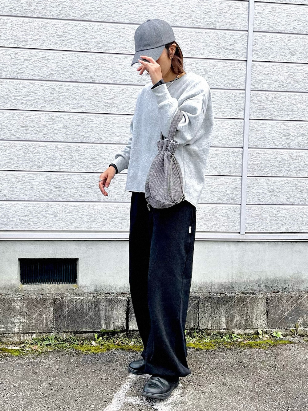 グレー系のハンドバッグ、ブラック系のスウェットパンツ、ブラック系のスニーカーを着用したレディースの秋コーディネートの1枚目の写真