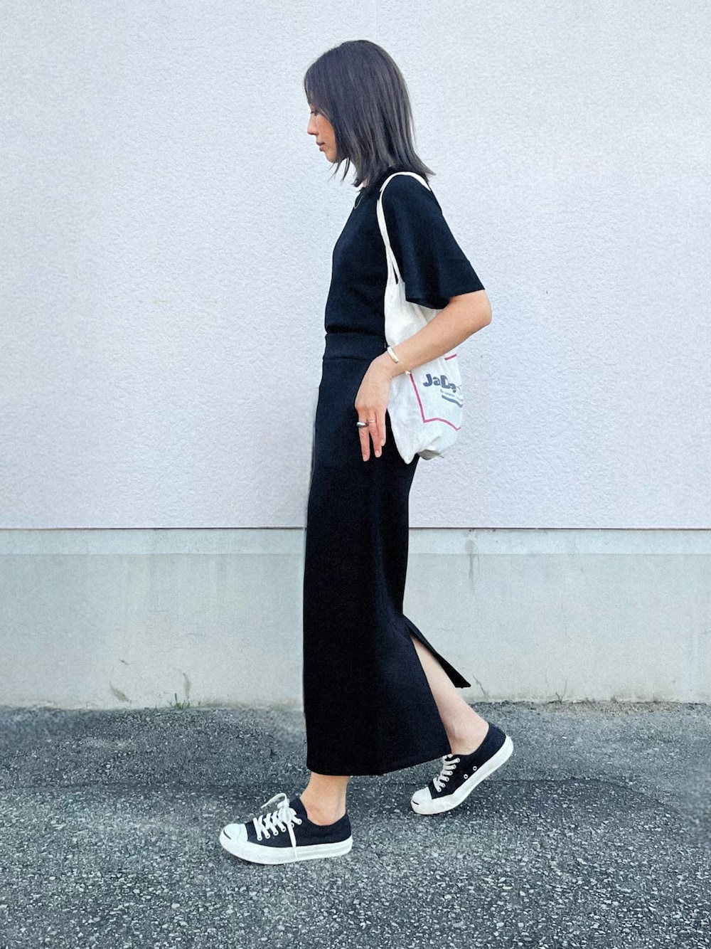 ブラック系のニット/セーター、ブラック系のスカート、ブラック系のスニーカーを着用したレディースの夏コーディネートの1枚目の写真