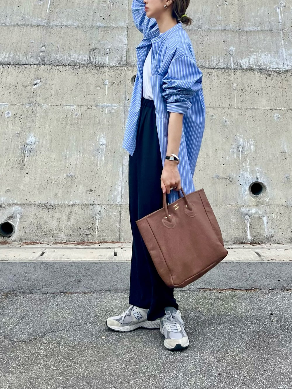 ブルー系のシャツ/ブラウス、ブラウン系のトートバッグ、グレー系のスニーカーを着用したレディースの春コーディネートの1枚目の写真
