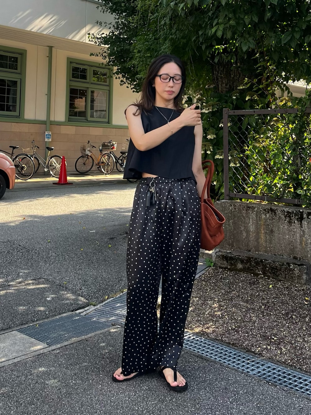 ブラック系のその他パンツ、ブラック系のサンダル、イエロー系のバッグを着用したレディースの夏コーディネートの1枚目の写真
