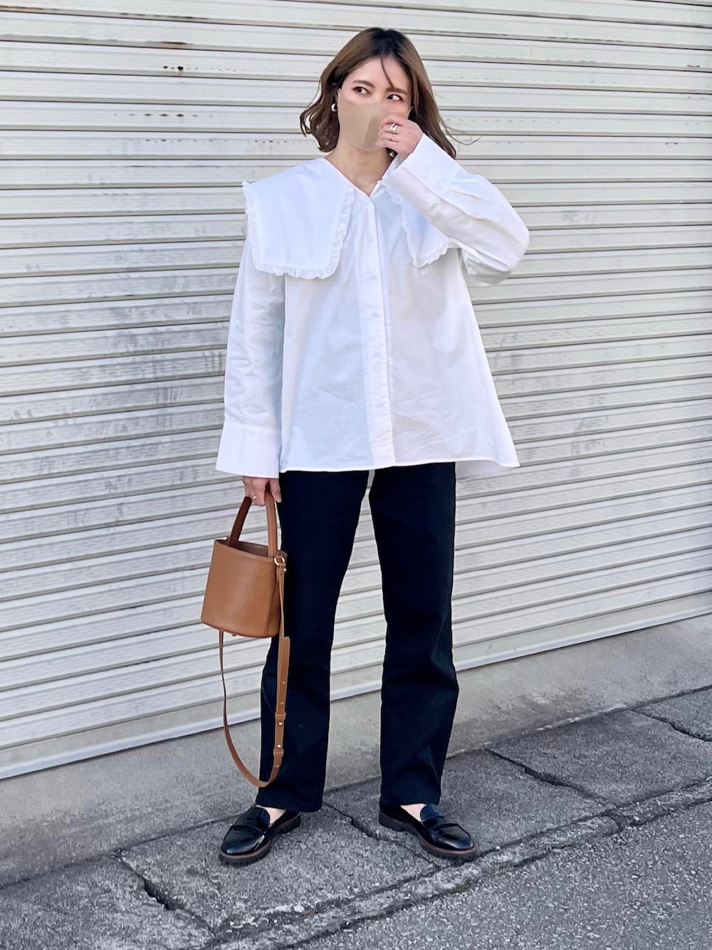 イエロー系のハンドバッグ、ブラック系のローファー、ブラック系のデニムパンツを着用したレディースの春コーディネートの1枚目の写真