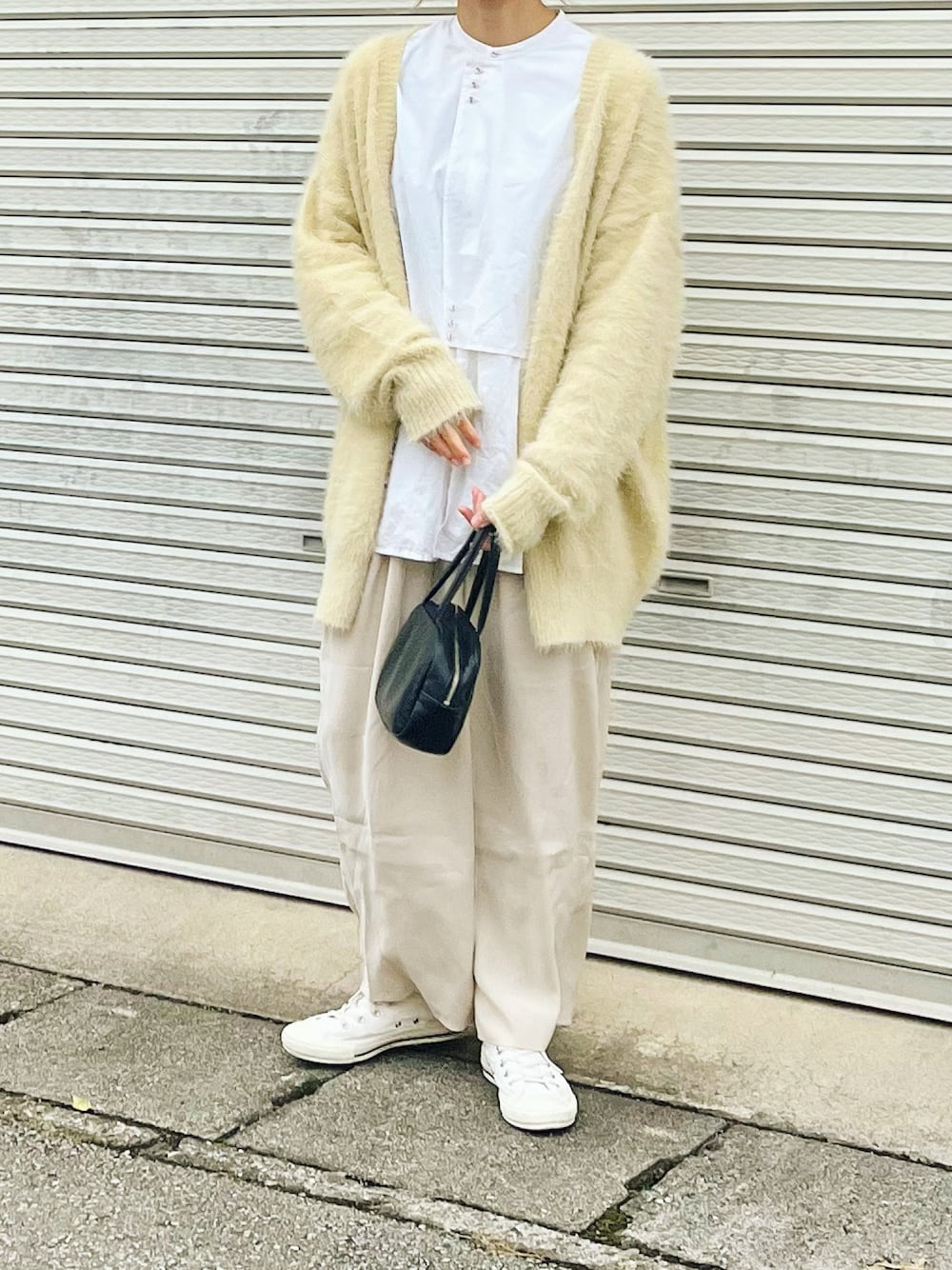 イエロー系のカーディガン/ボレロ、ホワイト系のシャツ/ブラウス、ブラック系のボストンバッグを着用したレディースの冬コーディネートの1枚目の写真