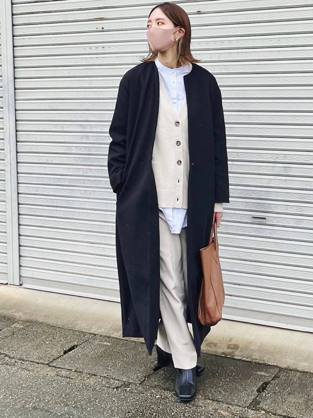 ブラック系のノーカラーコート、ホワイト系のカーディガン/ボレロ、ブラウン系のトートバッグを着用したレディースの冬コーディネートの1枚目の写真