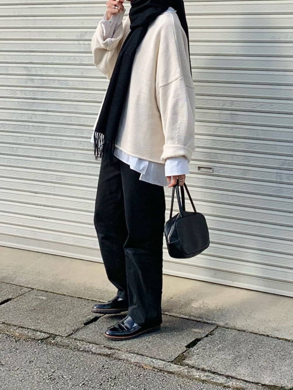 ホワイト系のニット/セーター、ホワイト系のシャツ/ブラウス、ブラック系のデニムパンツを着用したレディースの冬コーディネートの1枚目の写真