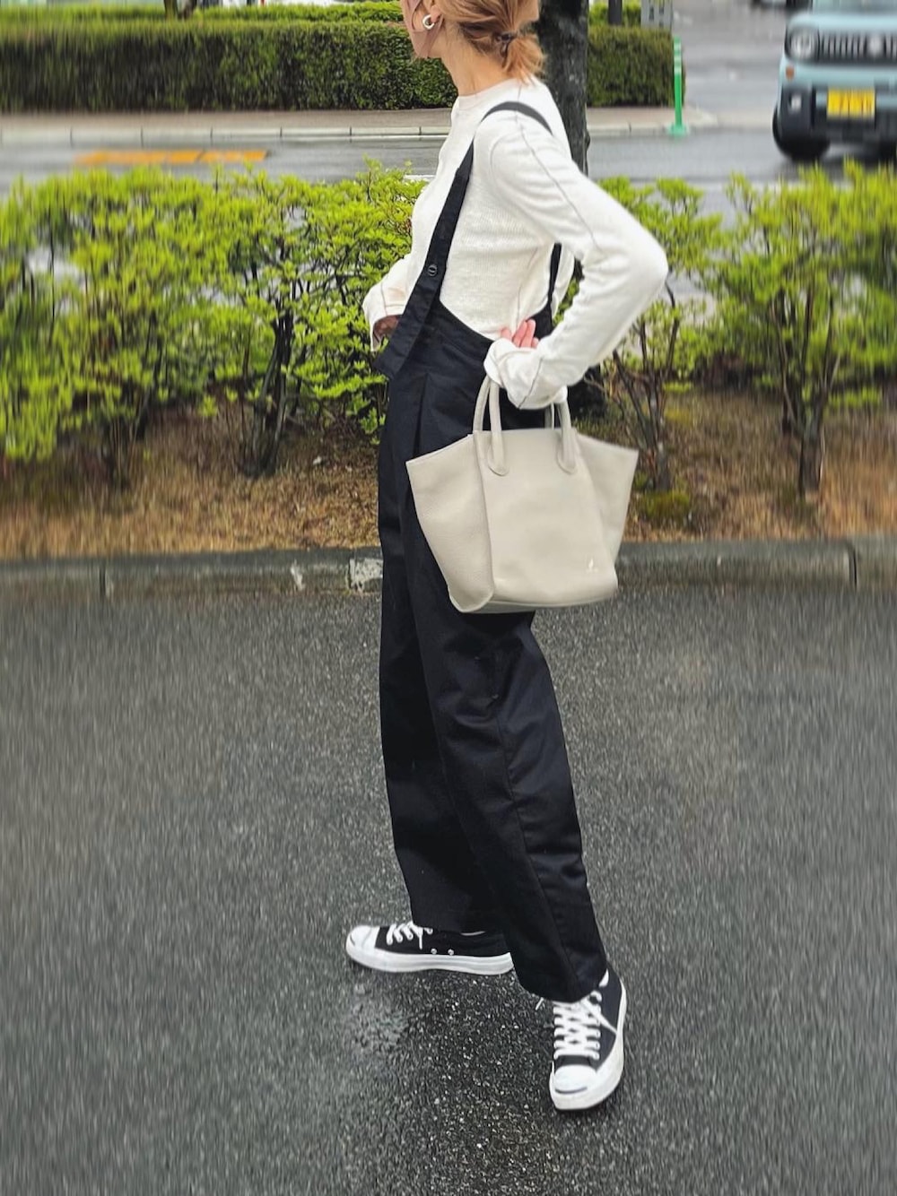 グレー系のバッグ、ホワイト系のTシャツ/カットソー、ブラック系のスニーカーを着用したレディースの春コーディネートの1枚目の写真