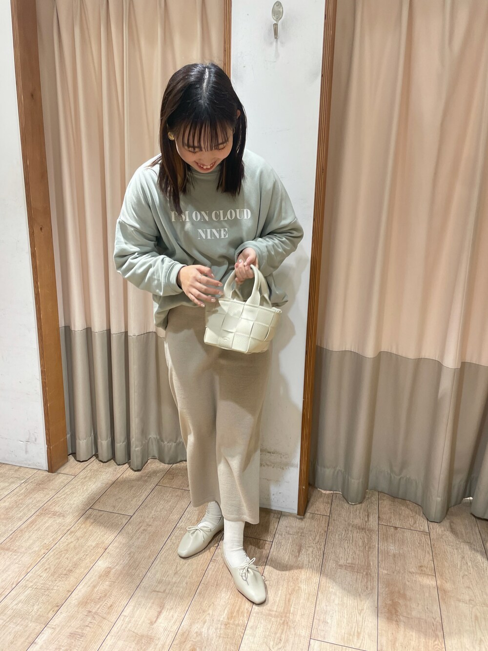 グリーン系のスウェット、ホワイト系のトートバッグ、ベージュ系のスカートを着用したレディースの冬コーディネートの1枚目の写真