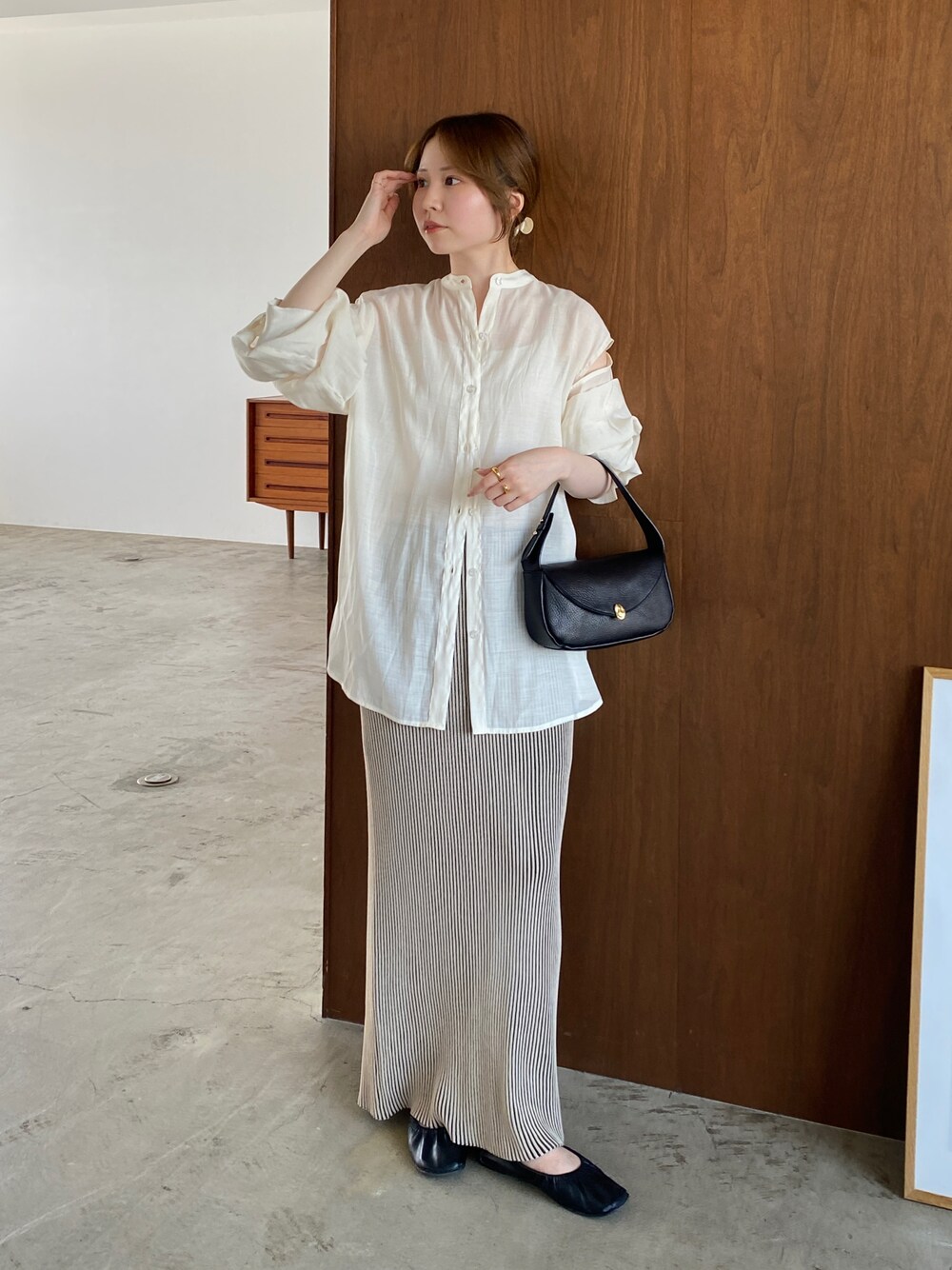 ブラック系のスカート、ホワイト系のシャツ/ブラウス、ブラック系のハンドバッグを着用したレディースの夏コーディネートの1枚目の写真