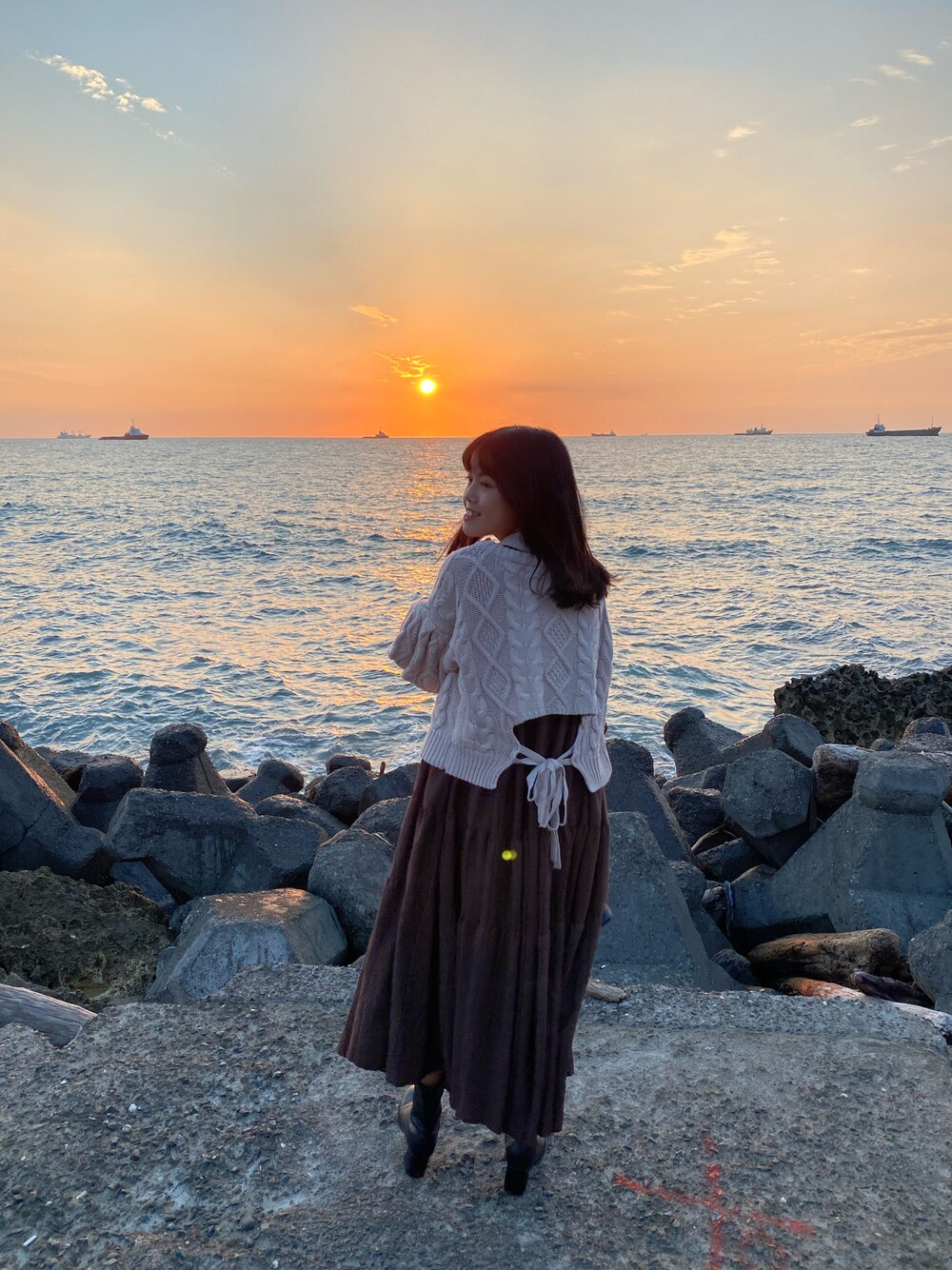 ブラウン系のワンピース、ホワイト系のニット/セーター、ブラック系のブーツを着用したレディースの秋コーディネートの1枚目の写真