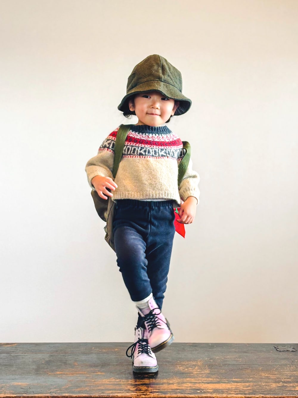 ベージュ系のニット/セーター、ブラック系のパンツ、グリーン系のバックパック/リュックを着用したキッズの秋コーディネートの1枚目の写真