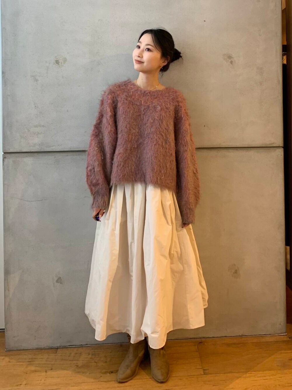 ピンク系のニット/セーター、ホワイト系のスカートを着用したレディースの秋コーディネートの1枚目の写真