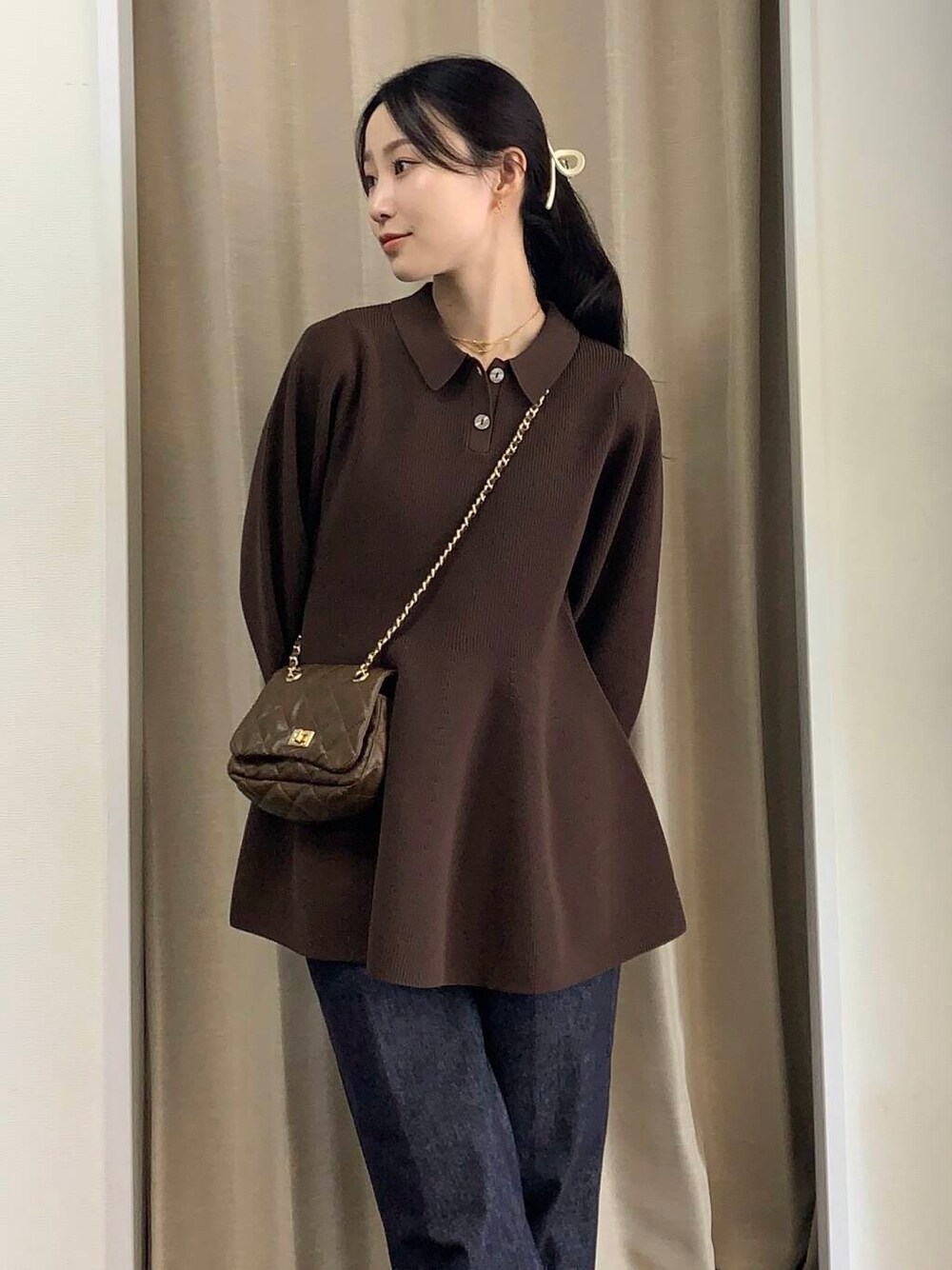 ブラウン系のショルダーバッグ、ブルー系のデニムパンツ、ブラウン系のニット/セーターを着用したレディースの秋コーディネートの1枚目の写真