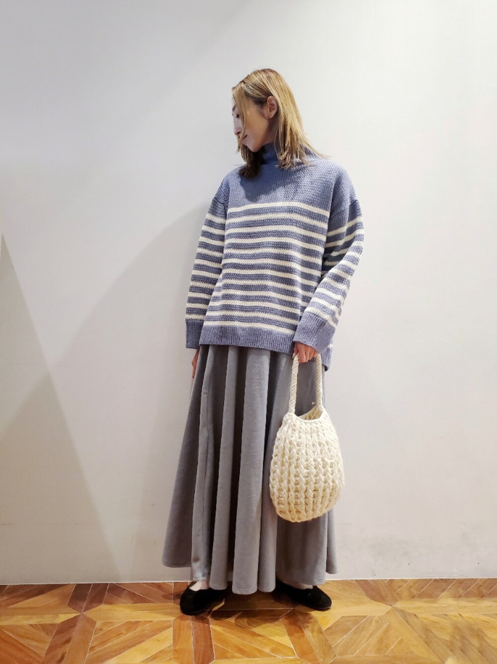 ブルー系のニット/セーター、グレー系のスカート、ホワイト系のショルダーバッグを着用したレディースの秋コーディネートの1枚目の写真