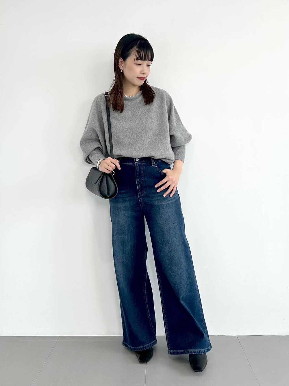 ブルー系のデニムパンツ、ブラック系のショルダーバッグ、ブラック系のパンプスを着用したレディースの秋コーディネートの1枚目の写真