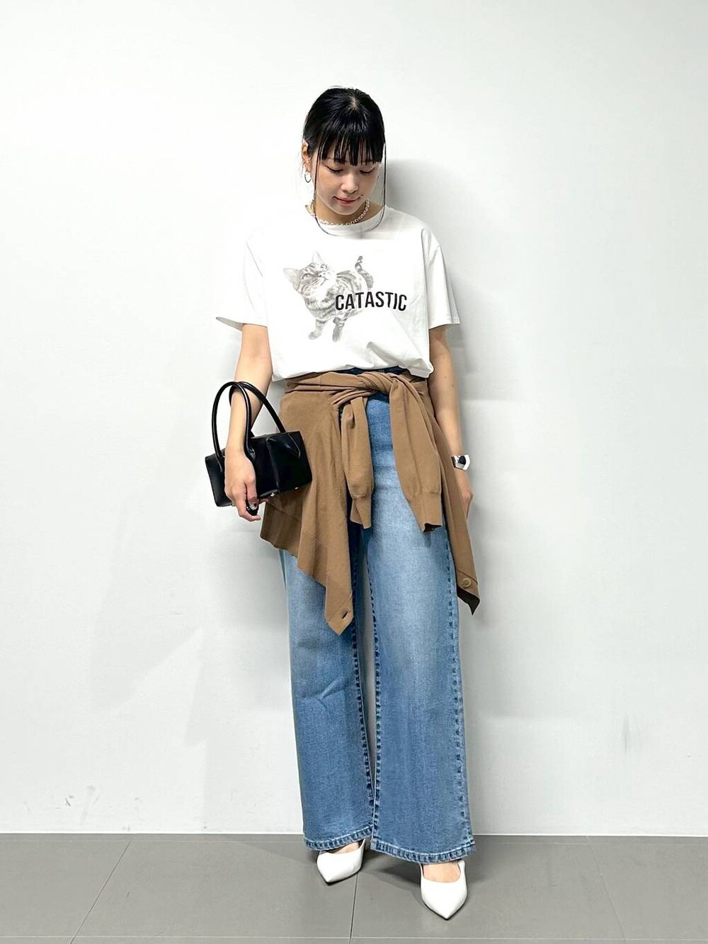 ブルー系のデニムパンツ、ブラック系のハンドバッグ、ホワイト系のTシャツ/カットソーを着用したレディースの夏コーディネートの1枚目の写真