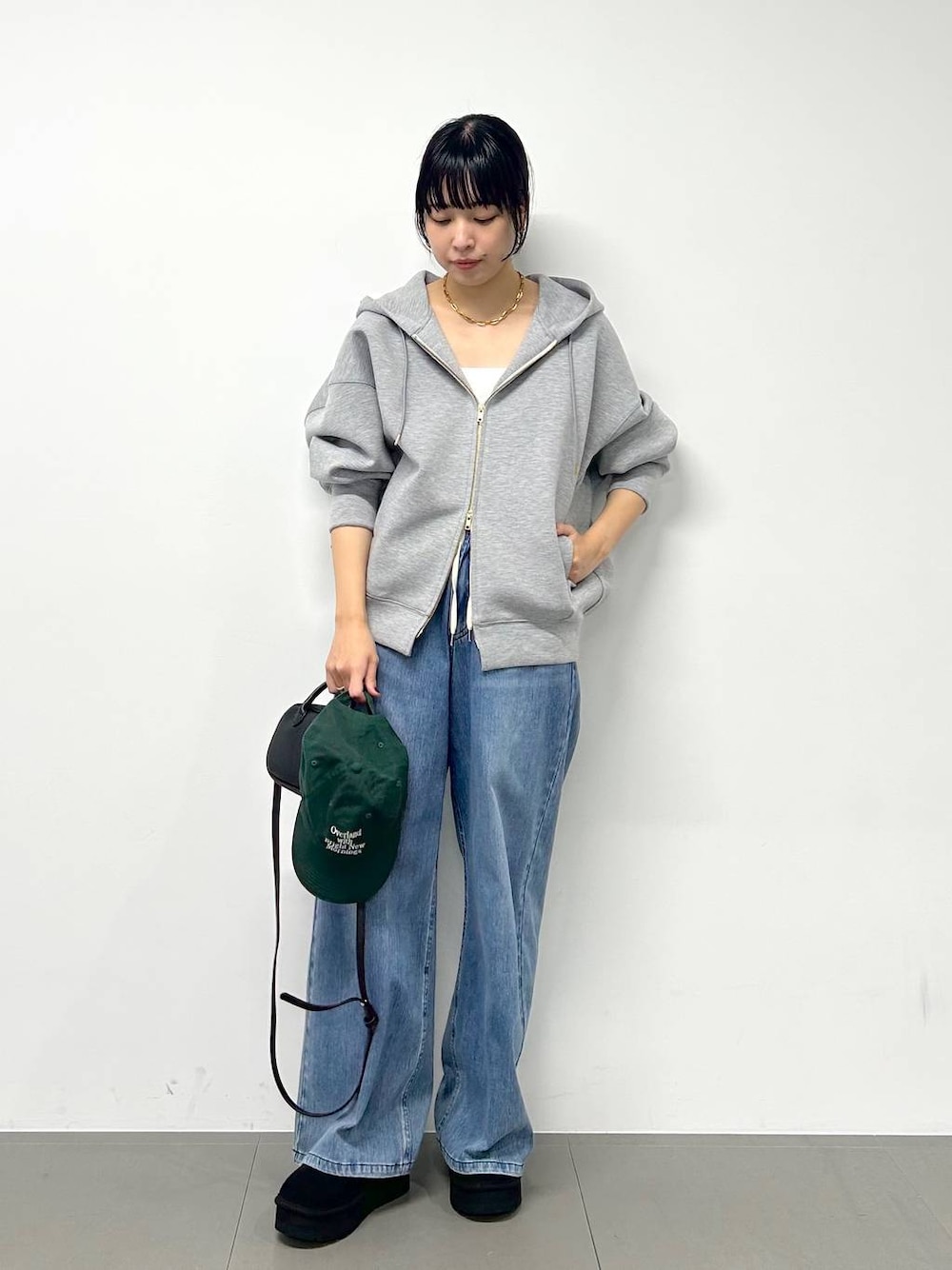 ブルー系のデニムパンツ、ブラック系のショルダーバッグ、グレー系のパーカーを着用したレディースの秋コーディネートの1枚目の写真