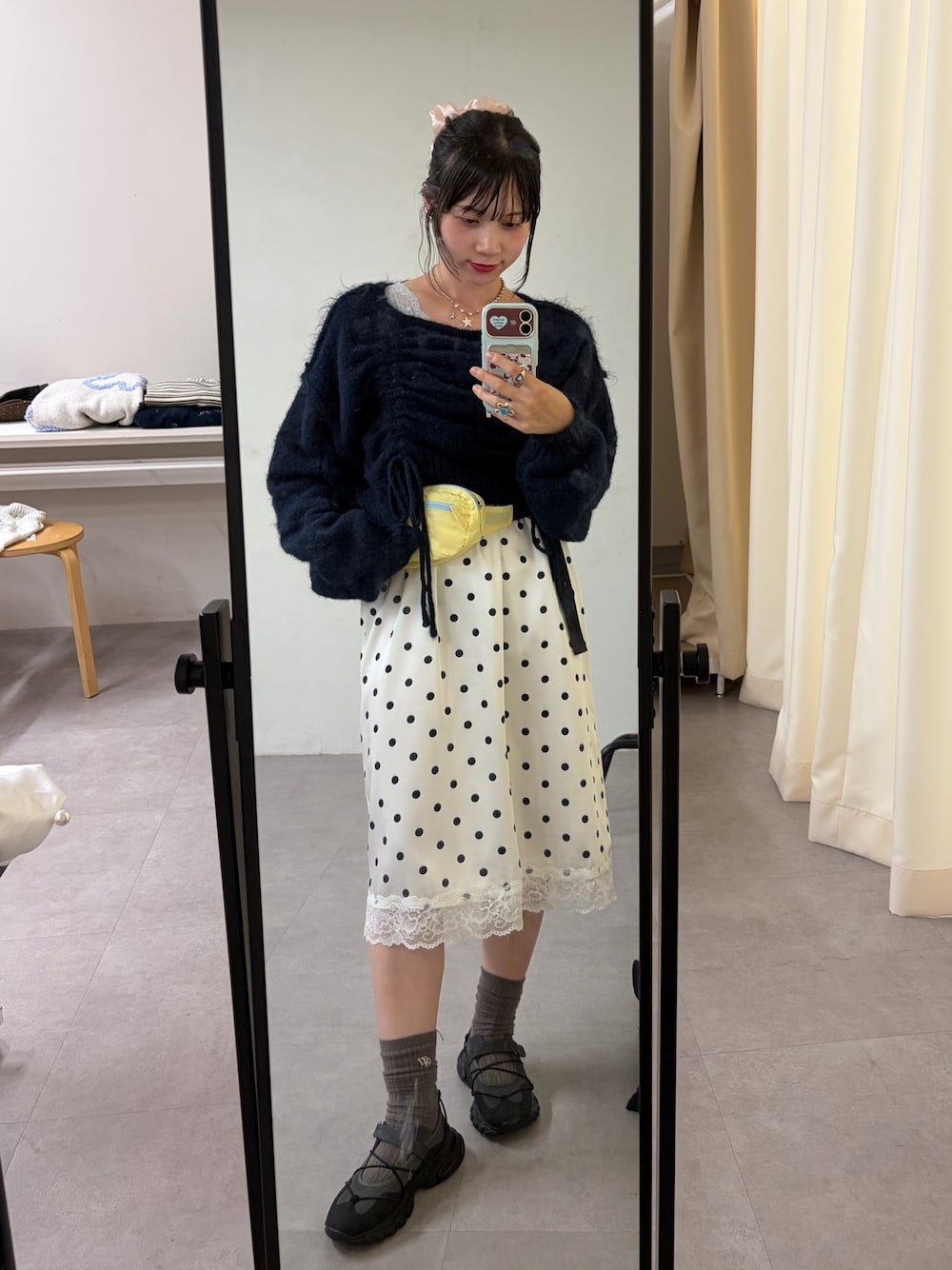 ブルー系のニット/セーター、ホワイト系のスカート、グレー系のスニーカーを着用したレディースの秋コーディネートの1枚目の写真