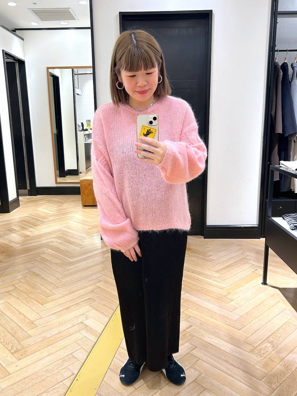 ブラック系のスニーカー、ブラック系のスカート、ピンク系のニット/セーターを着用したレディースの秋コーディネートの1枚目の写真