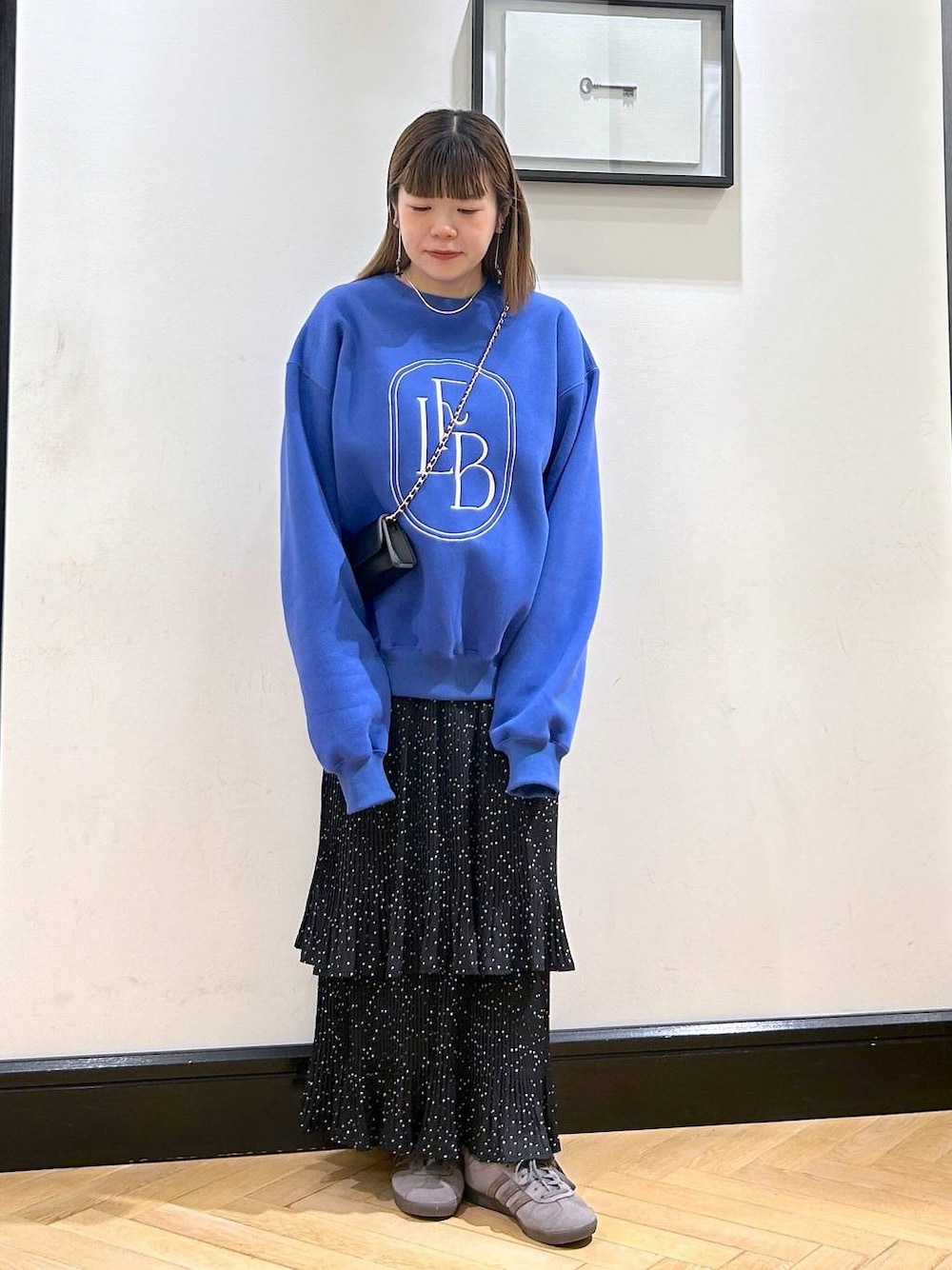 グレー系のスカート、グレー系のスニーカー、ブルー系のスウェットを着用したレディースの秋コーディネートの1枚目の写真