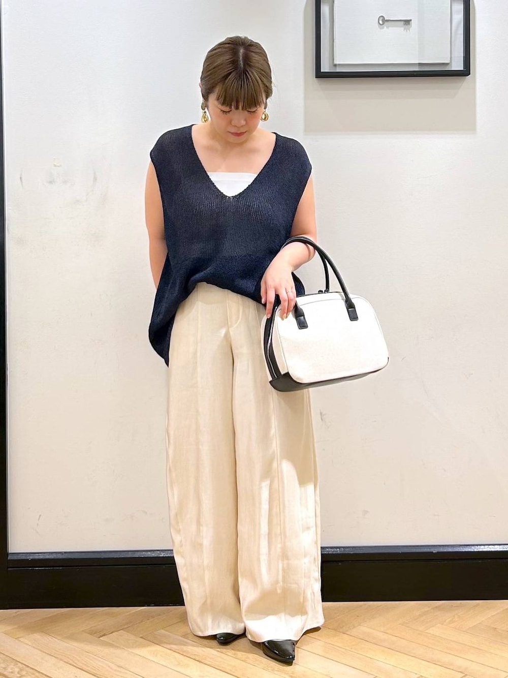 ブラック系のパンプス、ホワイト系のタンクトップ、ブラック系のボストンバッグを着用したレディースの夏コーディネートの1枚目の写真