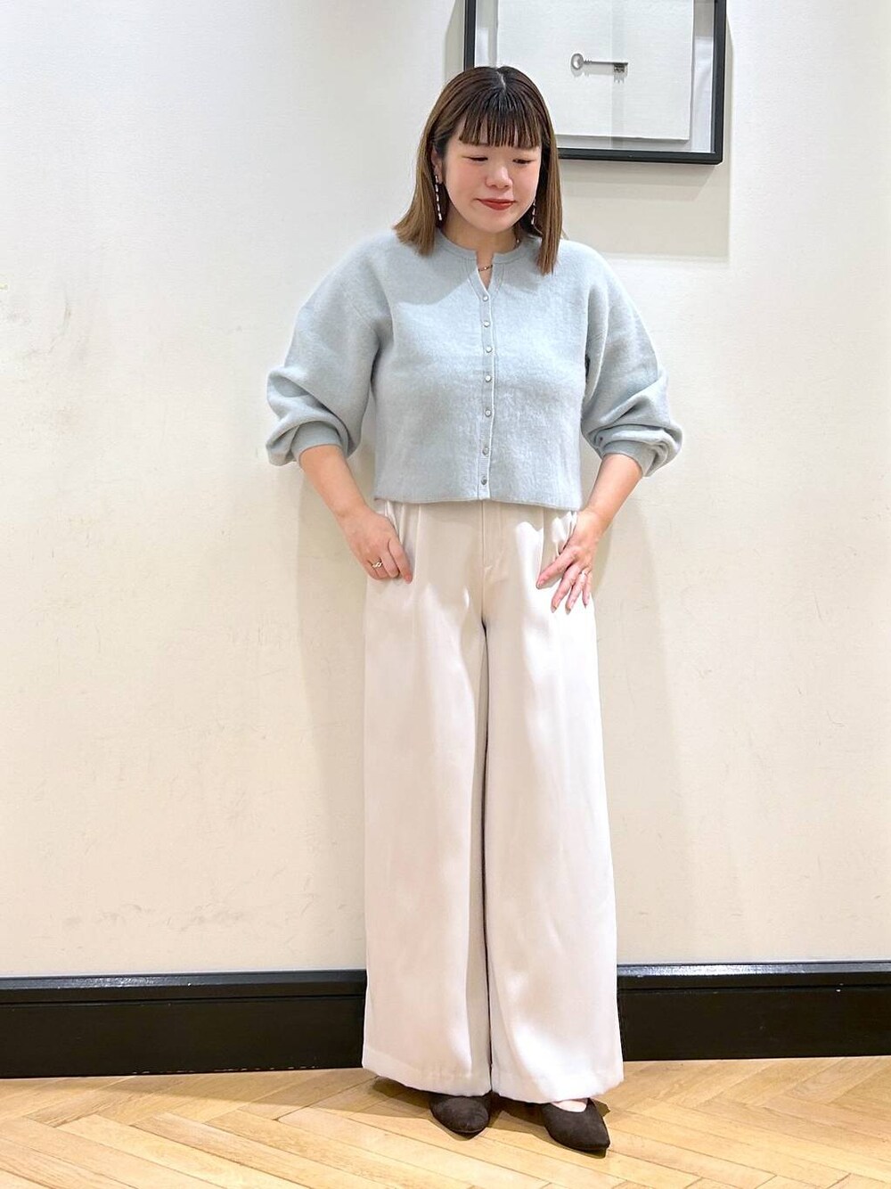 グリーン系のカーディガン/ボレロ、ホワイト系のスラックス、ブラウン系のパンプスを着用したレディースの秋コーディネートの1枚目の写真