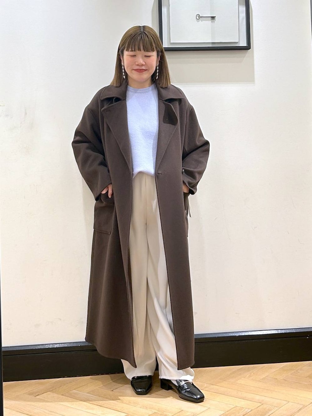 ブラウン系のステンカラーコート、ブラック系のローファー、ブルー系のニット/セーターを着用したレディースの秋コーディネートの1枚目の写真