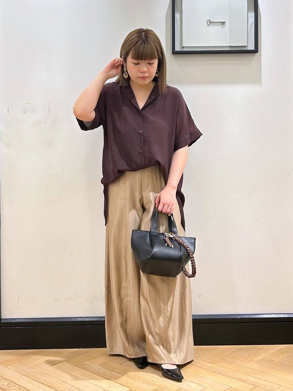 ブラウン系のシャツ/ブラウス、ブラック系のパンプス、ブラック系のハンドバッグを着用したレディースの夏コーディネートの1枚目の写真