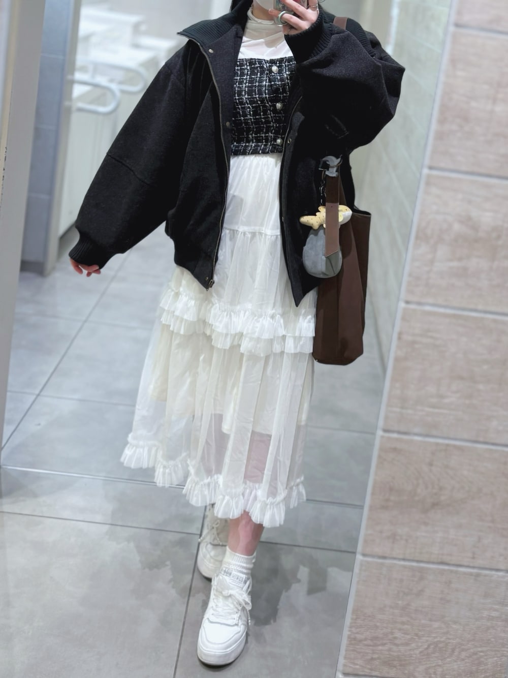 ブラック系のベスト、ブラック系のブルゾン、ホワイト系のスカートを着用したレディースの秋コーディネートの1枚目の写真