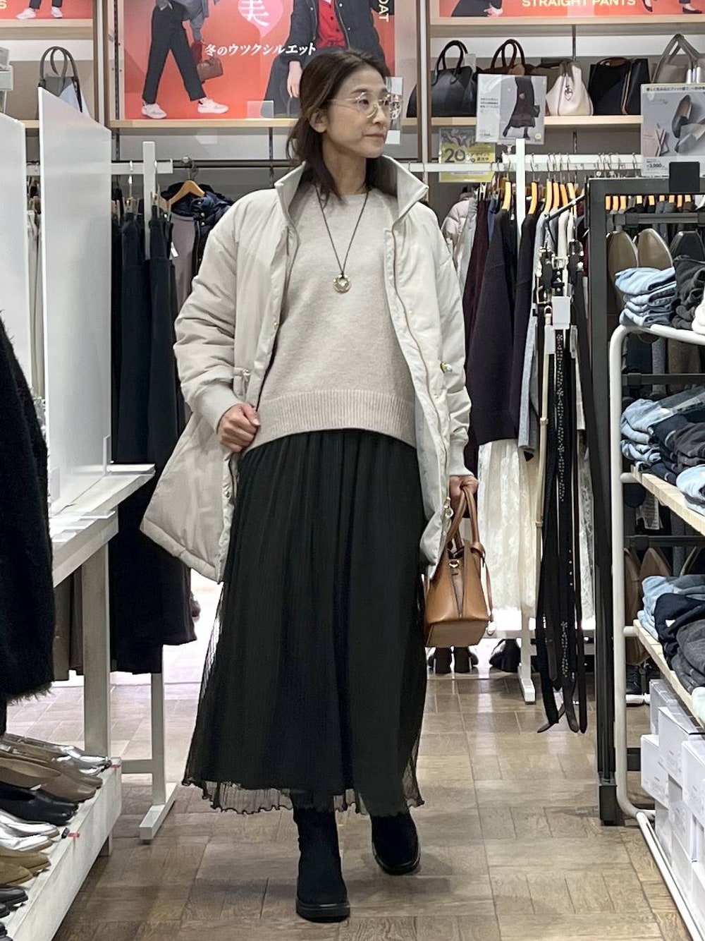 ブラウン系のショルダーバッグ、ベージュ系のダウンジャケット/コート、グレー系のワンピースを着用したレディースの秋コーディネートの1枚目の写真