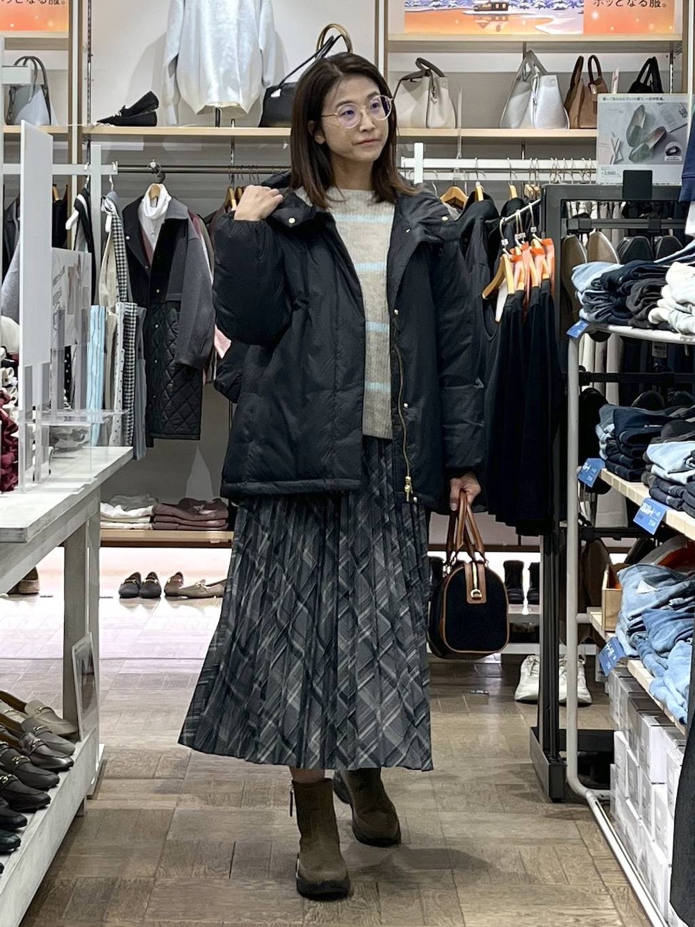 ブラック系のダウンジャケット/コート、ブラウン系のブーツ、ベージュ系のニット/セーターを着用したレディースの冬コーディネートの1枚目の写真