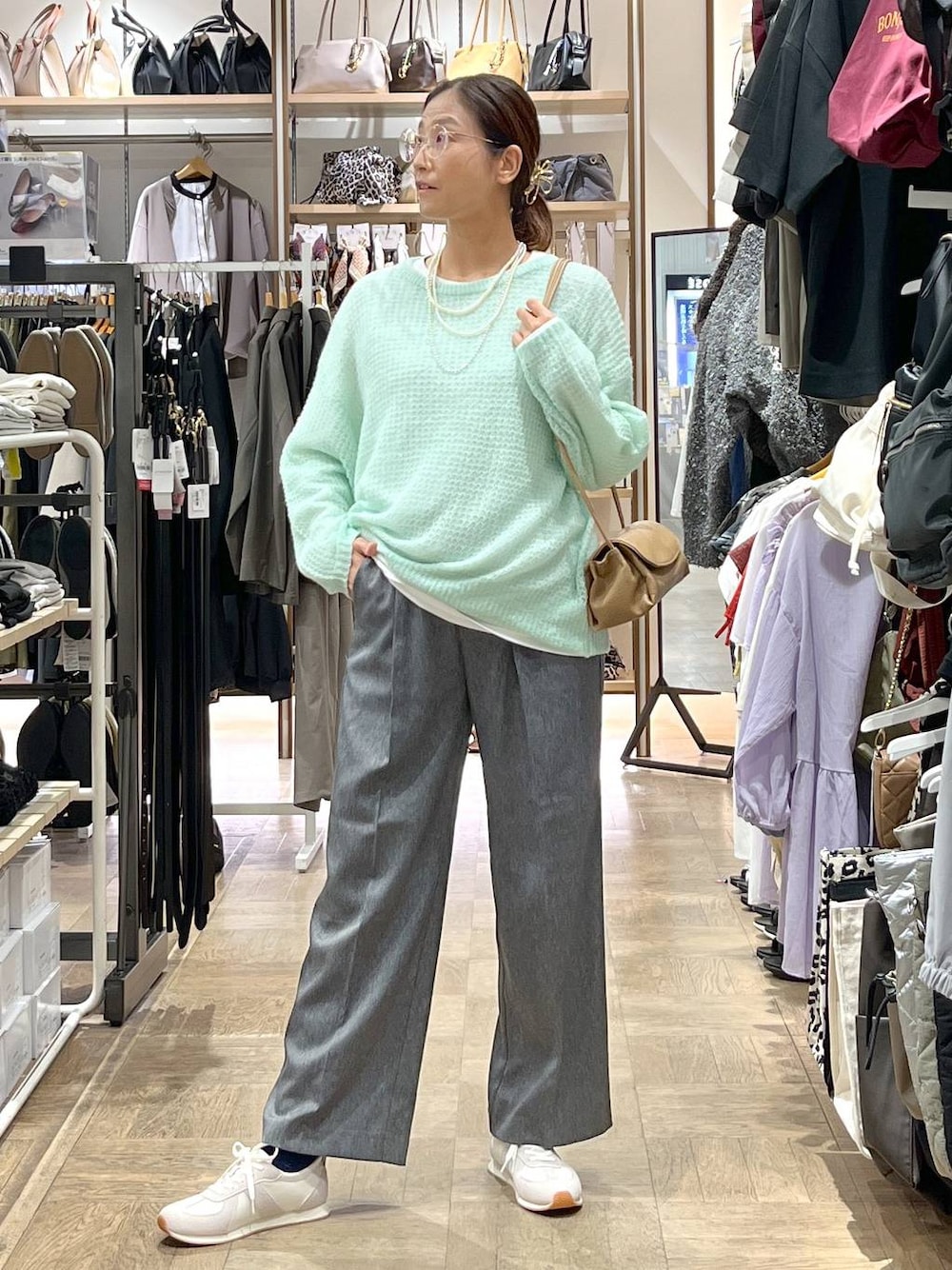 グレー系のその他パンツ、ベージュ系のスニーカー、グリーン系のニット/セーターを着用したレディースの秋コーディネートの1枚目の写真