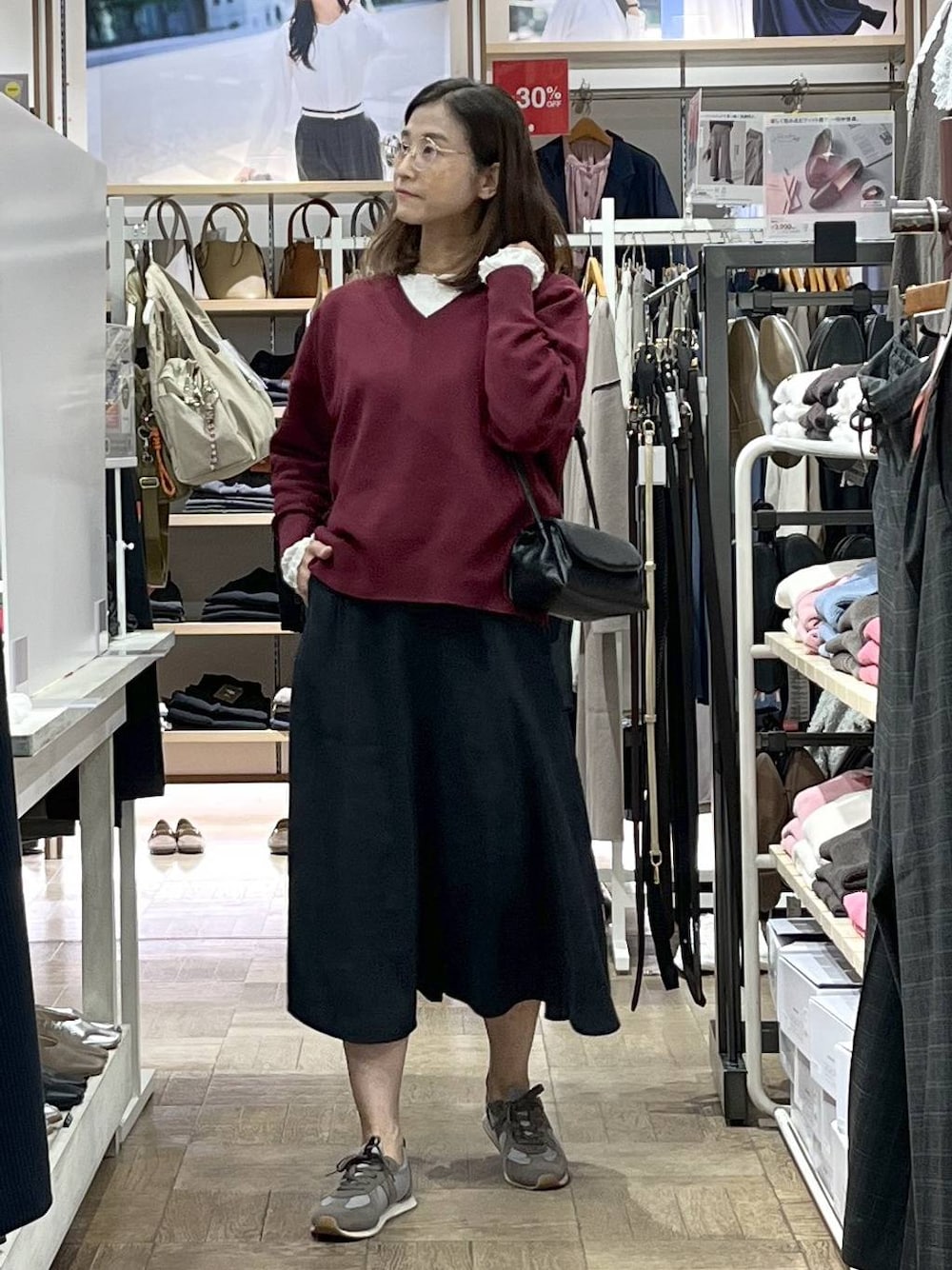 レッド系のスウェット、グレー系のスカート、グレー系のスニーカーを着用したレディースの秋コーディネートの1枚目の写真