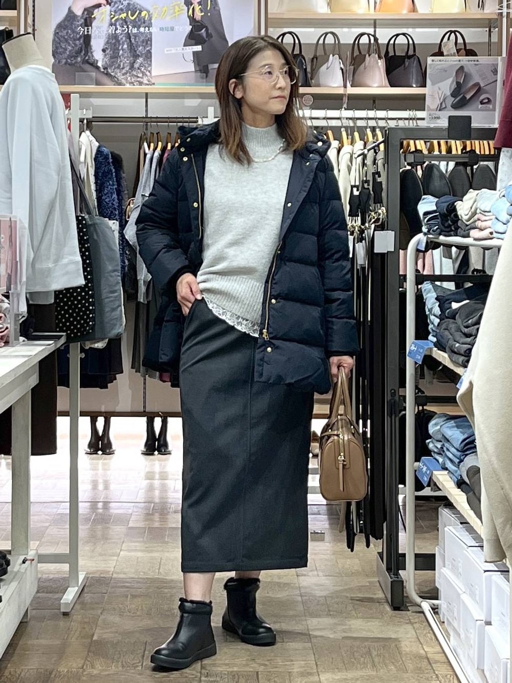 ブルー系のダウンジャケット/コート、グレー系のスカート、シルバー系のニット/セーターを着用したレディースの冬コーディネートの1枚目の写真