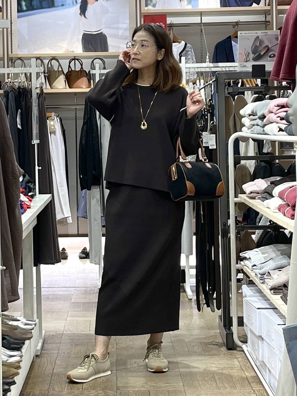 ベージュ系のスニーカー、ブラウン系のワンピース、ブラック系のボストンバッグを着用したレディースの秋コーディネートの1枚目の写真