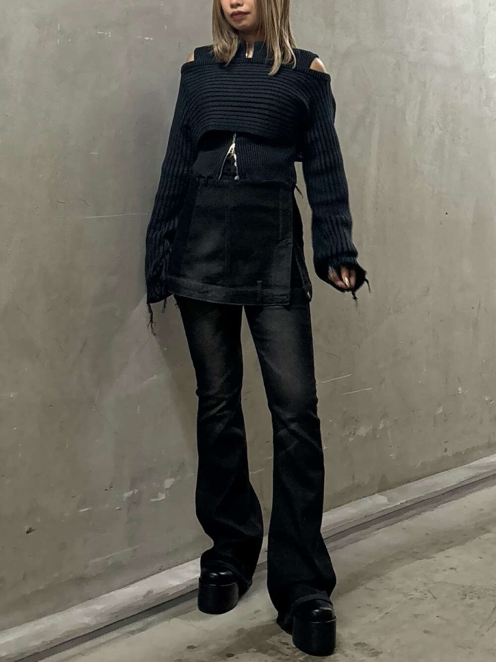 ブラック系のニット/セーター、ブラック系のデニムパンツ、ブラック系のブーツを着用したレディースの秋コーディネートの1枚目の写真