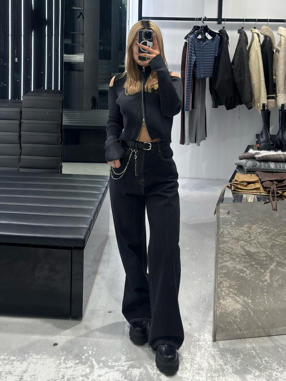 ブラック系のニット/セーター、ブルー系のデニムパンツ、ブラック系のブーツを着用したレディースの冬コーディネートの1枚目の写真