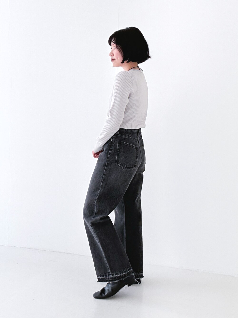 ブラック系のデニムパンツ、ブラック系のブーツ、グレー系のニット/セーターを着用したレディースの冬コーディネートの1枚目の写真