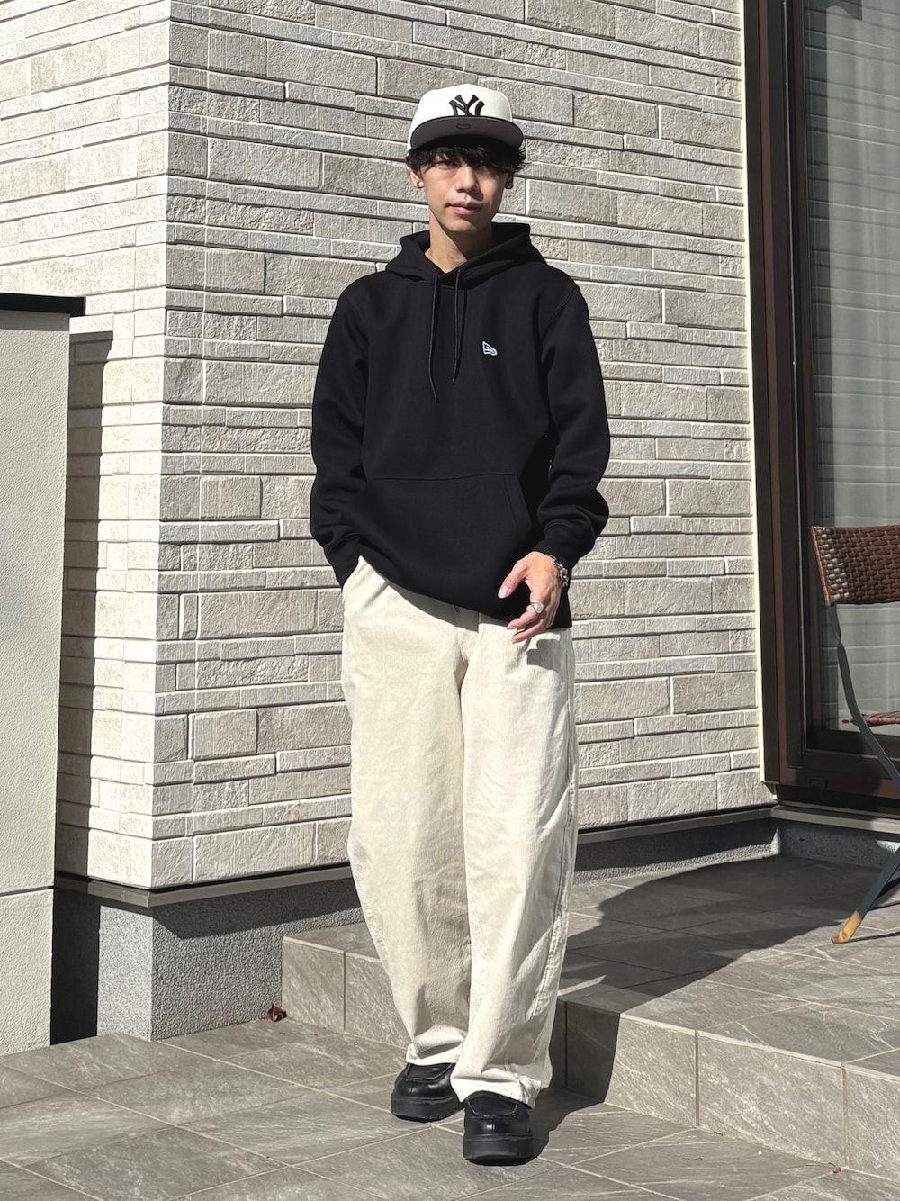 ブラック系のパーカー、ブラック系のローファー、ホワイト系のキャップを着用したメンズの冬コーディネートの1枚目の写真