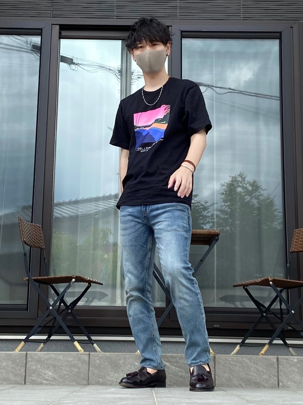 ブルー系のデニムパンツ、ブラック系のTシャツ/カットソー、ブラウン系のローファーを着用したメンズの夏コーディネートの1枚目の写真