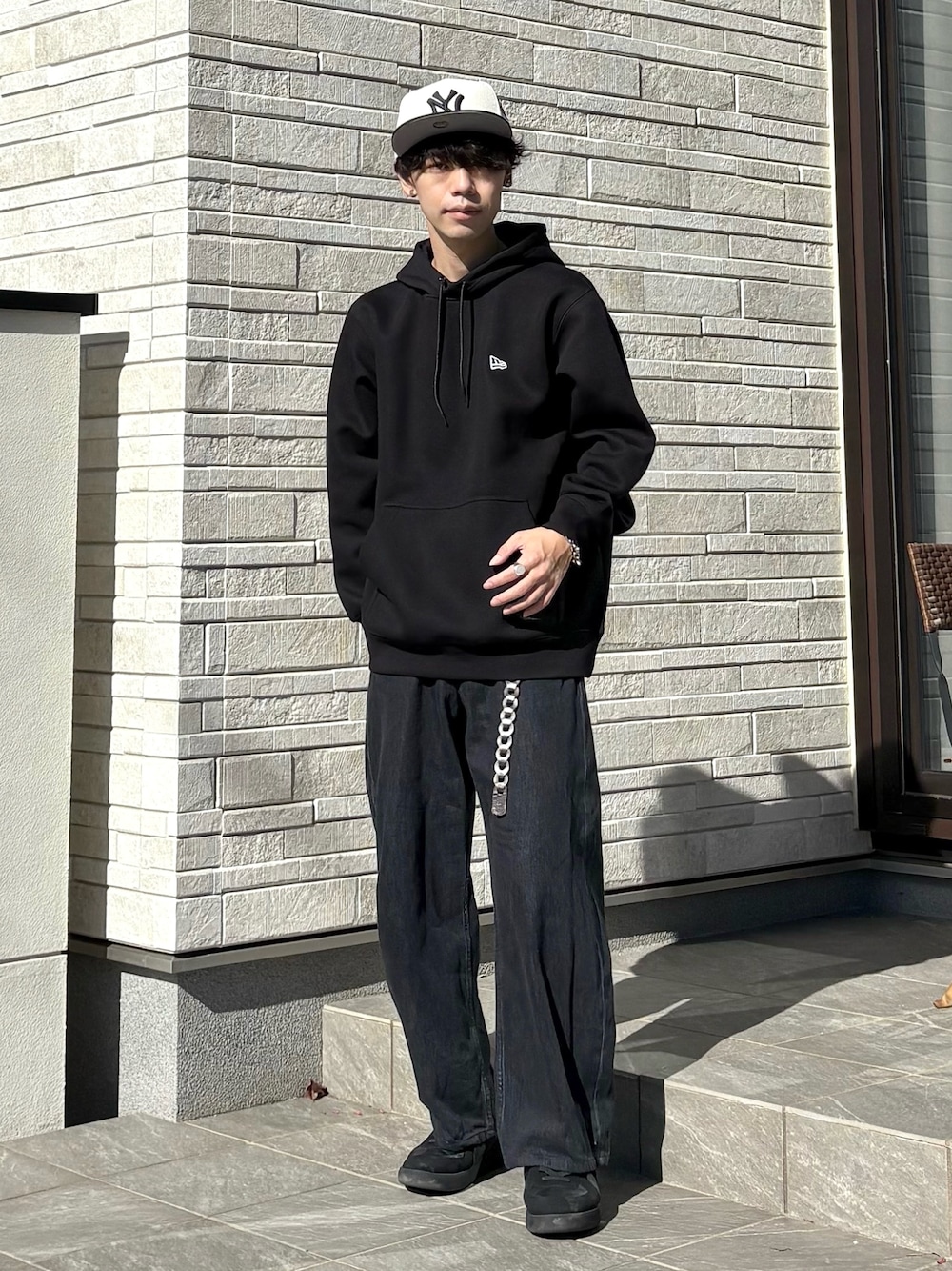 ブラック系のパーカー、ホワイト系のキャップ、グレー系のベルトを着用したメンズの冬コーディネートの1枚目の写真