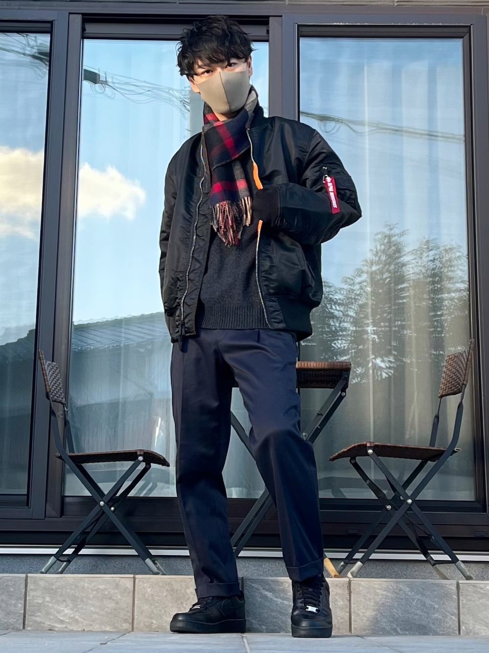 ブラック系のMA-1、ブラック系のニット/セーター、ブルー系のスラックスを着用したメンズの冬コーディネートの1枚目の写真