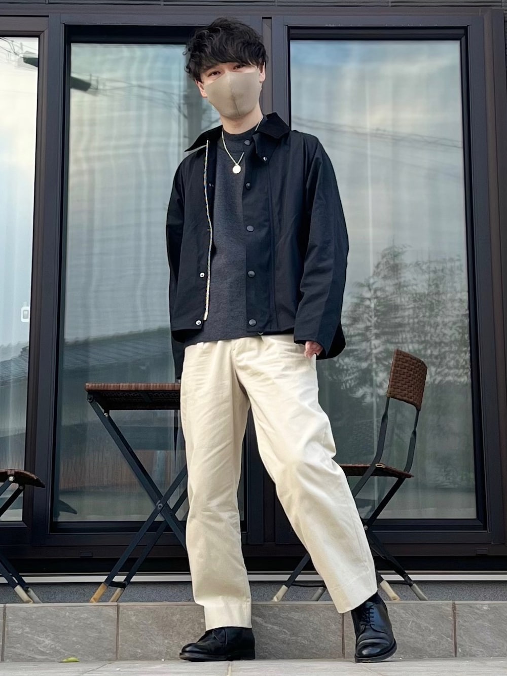 ブラック系のブルゾン、ブラック系のニット/セーター、ベージュ系のスラックスを着用したメンズの春コーディネートの1枚目の写真