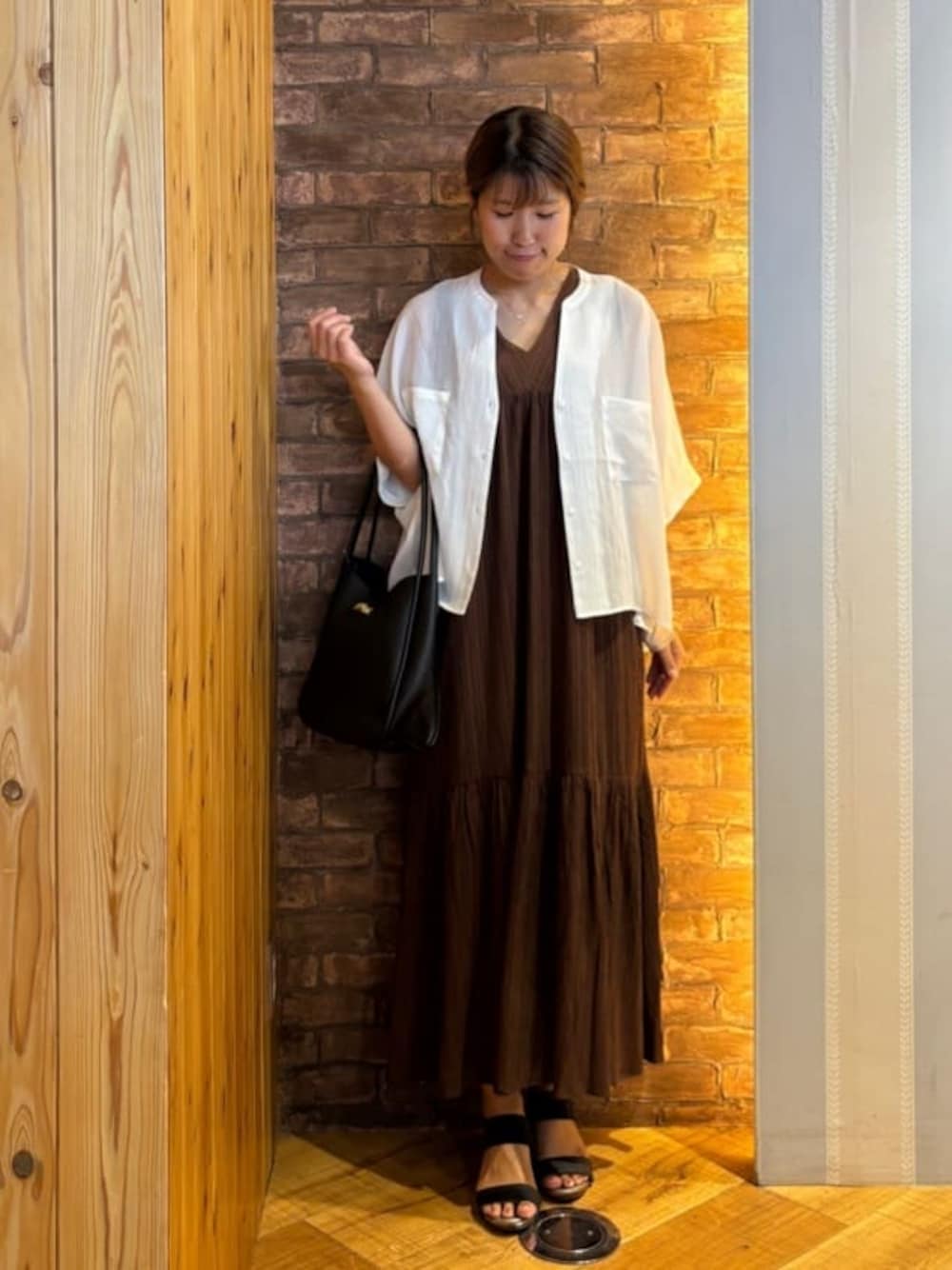 ホワイト系のシャツ/ブラウス、ブラウン系のワンピース、ブラック系のサンダルを着用したレディースの夏コーディネートの1枚目の写真