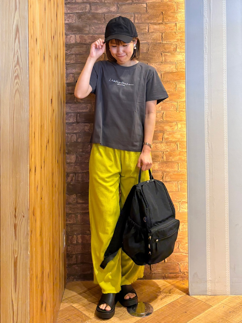 グレー系のTシャツ/カットソー、イエロー系のその他パンツ、ブラック系のサンダルを着用したレディースの春コーディネートの1枚目の写真