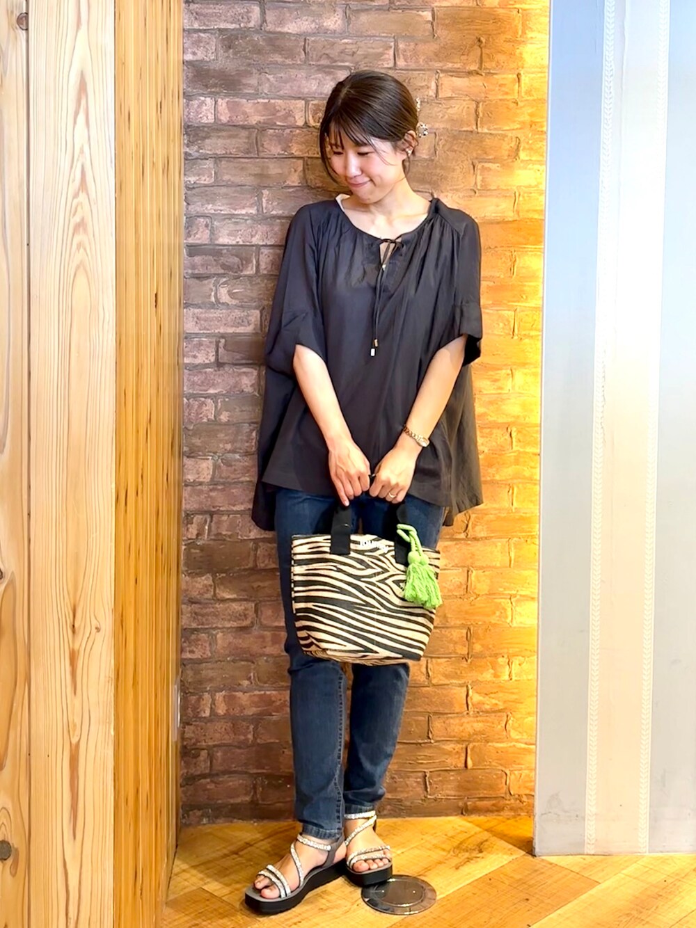 ブルー系のデニムパンツ、グレー系のサンダル、ブラック系のトートバッグを着用したレディースの夏コーディネートの1枚目の写真