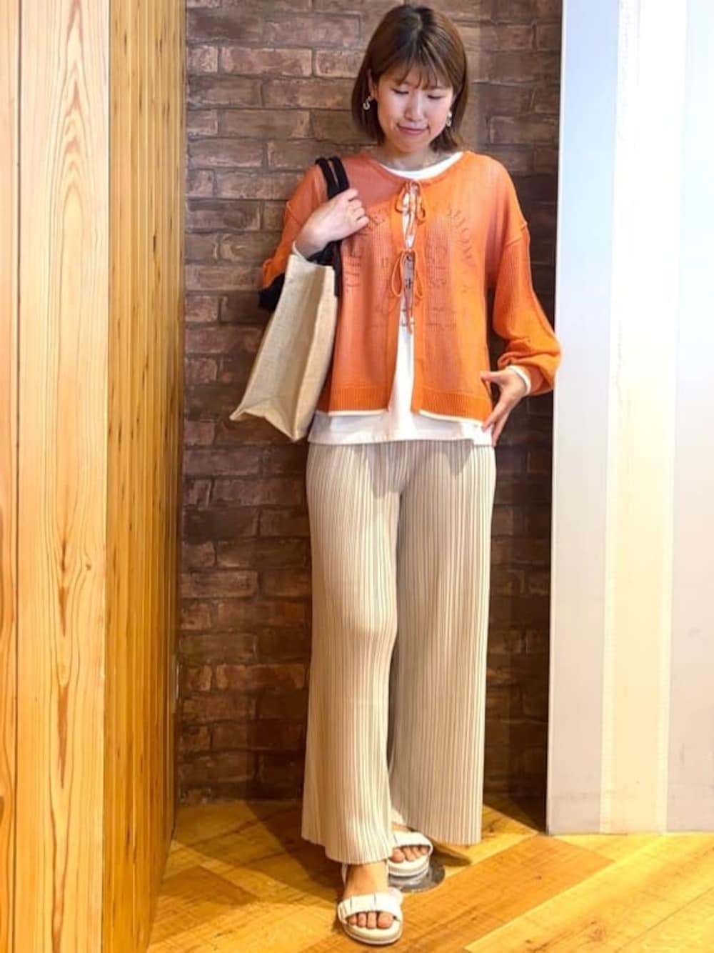 オレンジ系のその他トップス、ホワイト系のその他パンツ、ホワイト系のサンダルを着用したレディースの春コーディネートの1枚目の写真