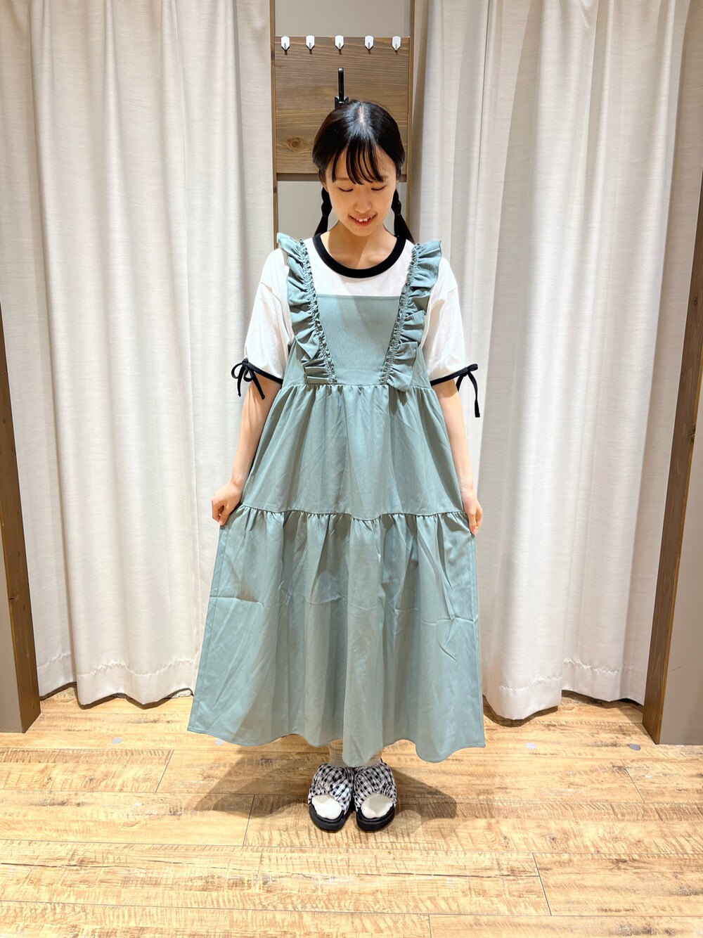 グリーン系のワンピース、ホワイト系のTシャツ/カットソー、ブラック系のサンダルを着用したレディースの夏コーディネートの1枚目の写真