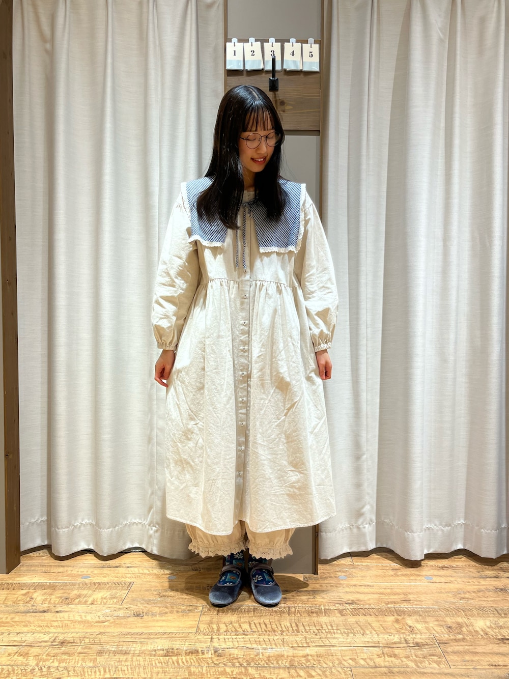ベージュ系のワンピース、グレー系のドレスシューズ、ブルー系のシャツ/ブラウスを着用したレディースの冬コーディネートの1枚目の写真