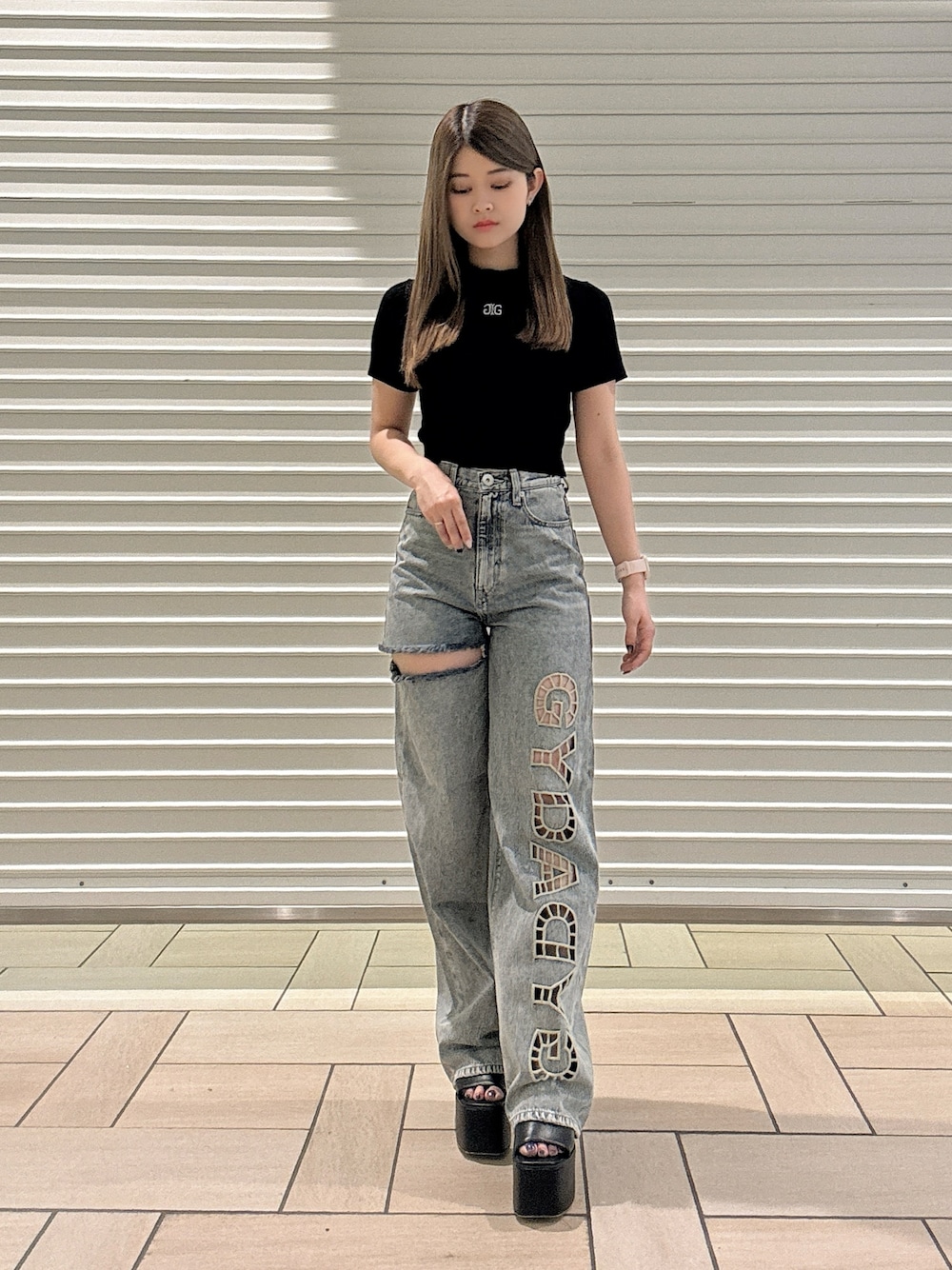 ブラック系のTシャツ/カットソー、ブルー系のデニムパンツ、ブラック系のサンダルを着用したレディースの春コーディネートの1枚目の写真
